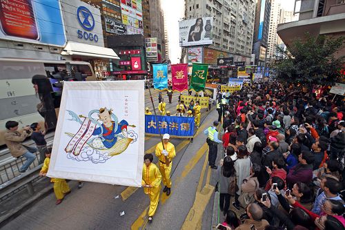 学员举起真相海报与横幅走过闹市,吸引大批民众围观。