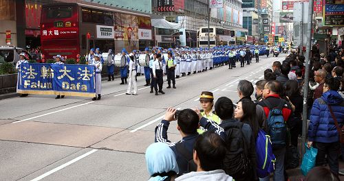 法轮功阵容庞大整齐的游行队伍吸引中西游客及港民驻足观看,纷纷举起相机、手机拍照。