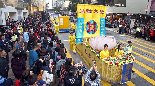 法轮功阵容庞大整齐的游行队伍吸引中西游客及港民驻足观看,纷纷举起相机、手机拍照。