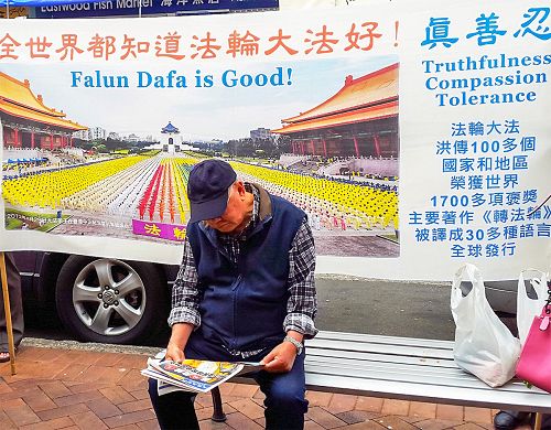 图2:一华人坐在真相横幅前阅读真相报纸