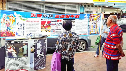 图4:过往的华人驻足观看真相横幅