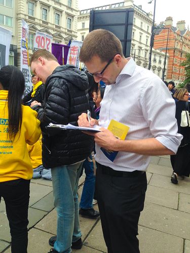 图9:二零一五年十月二十二日下午,住在伦敦的电影制片人罗宾(Robin)在谴责中共活摘法轮功学员器官的征签表上签字