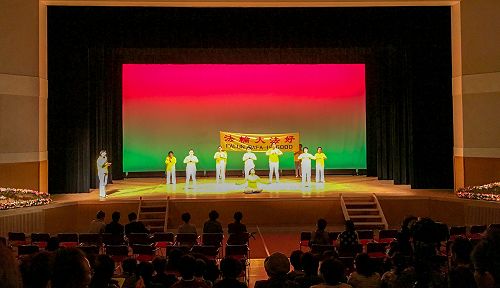 图1:法轮功学员在饭岛町文化节舞台上演示法轮功功法,并有学员在一旁解说。