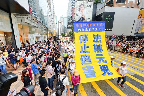 图:十月一日,香港法轮功学员举行“法办元凶、停止迫害”的集会游行,途中许多大陆游客被游行的场面震撼。