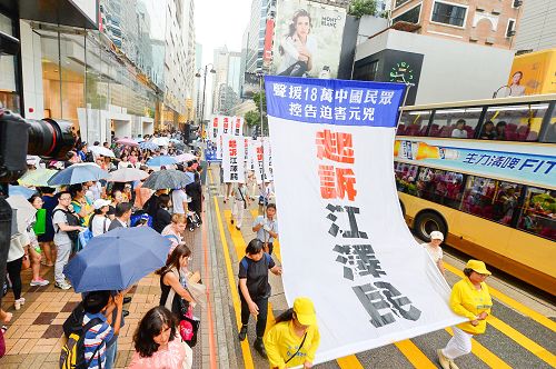 图:许多大陆游客被游行的巨大横幅标语”控诉江泽民”所震撼。