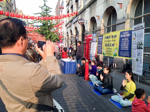 图10:一位中年华人男士认真摄下法轮功学员的炼功场面和真相横幅。