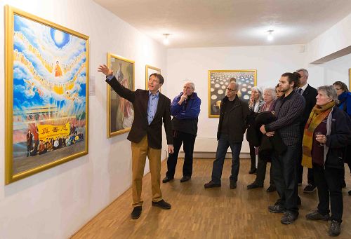 图5:画展观众认真倾听解说员介绍画作背后的故事、及所表达的内涵。