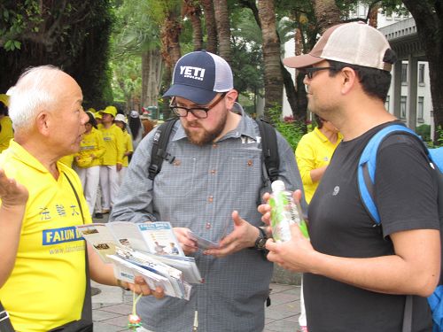 图6-10:中西游客及路人驻足拿取资料并聆听法轮功学员讲真相。