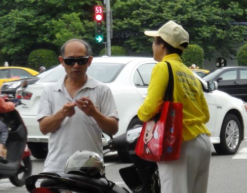 图5:法轮功学员为专程停车了解活动的民众讲述真相。