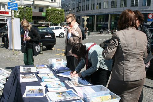 图1-3:在欧洲议会大厦前举办讲真相活动,很多民众在“反对活摘法轮功学员人体器官的征签簿”上签名