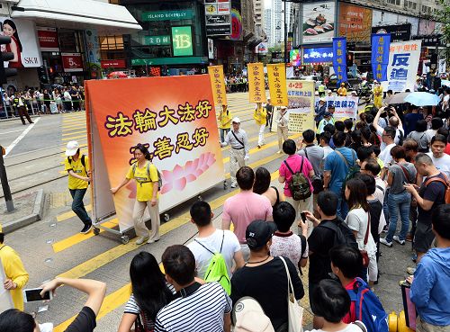 图5-10:法轮功学员的游行队伍在天团乐团引领下,走过港岛区闹市街道,吸引港民及中西游客驻足观看及拍照。