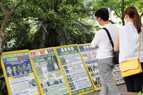 图8:旅客在真相版面前关注法轮功学员遭迫害真相。
