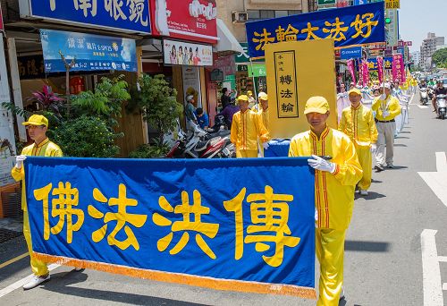 庆祝活动展开《转法轮》巨型模型,学员们精神抖擞举着“法轮大法好”横幅,与民众分享喜悦。