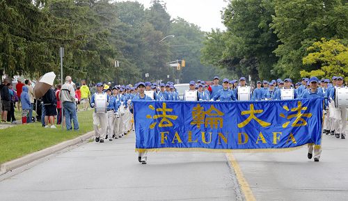 图4-5:六月十四日,多伦多法轮功学员组成的天国乐团和腰鼓队应邀参加伯灵顿音乐节游行 (Burlington Sound of Music Festival Parade)受欢迎。人们打着雨伞在热烈的欢迎他们的到来。