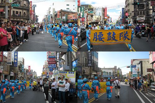 人们围在道路两旁观看腰鼓队的表演,并拍照。