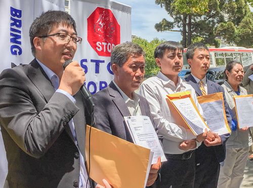 图:法轮功学员在中领馆前宣读对江泽民的控告状