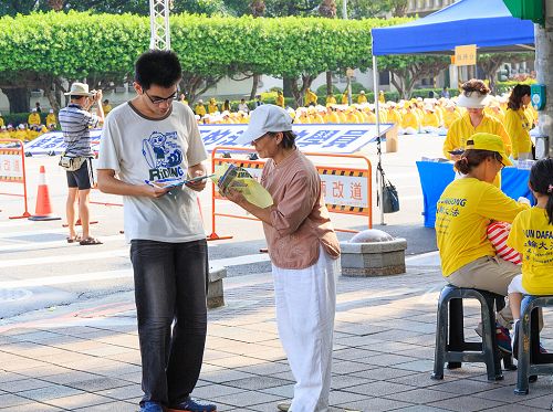 图9:学员(右)给过往的民众讲述江泽民迫害法轮功的真相,民众签名联署刑事举报江泽民。