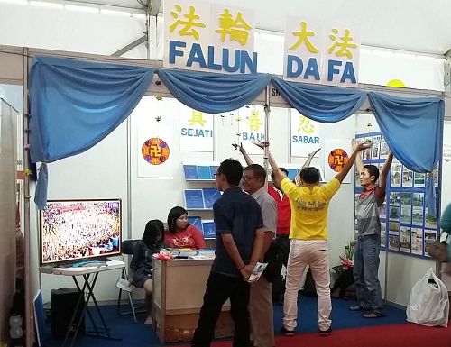 图1-2:印尼法轮功学员在雅加达书籍和教育展览会上设立展位,向大众介绍法轮大法及相关大法书籍。有的民众现场学功。