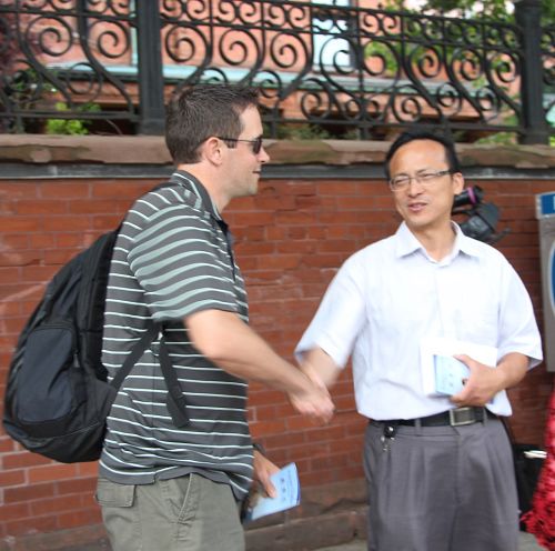 Dwight(左)是一名基督徒,他跟法轮功学员紧紧地握手,说:“谢谢让我知道了这些真相!”
