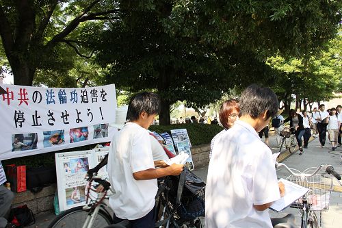 人们驻足观看真相展板,或和学员交谈了解真相
