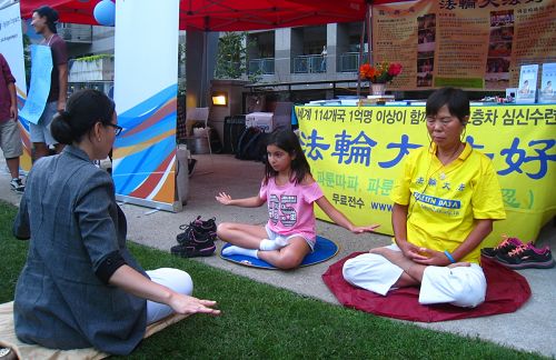 图8-9:两天活动中,不少民众现场学炼功法,其中有二十多人说下周六会到位于这个广场的炼功点来学炼法轮功。图为现场民众正在学功。