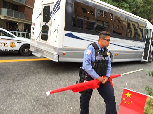 图4 :有几个人试图用旗子遮挡住法轮功学员手中的横幅,一位警察没收了一人的旗子,并折断了旗杆。