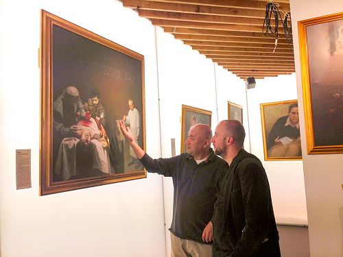 图5:制片人维森特(Vicent)(右)和世界维吾尔族大会英国代表安华·托蒂(左)一起在观看画作《活摘器官的罪恶》。