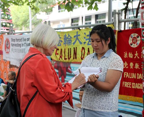 图1-4:二零一五年十二月三十一日晚,在墨尔本市中心迎接新年到来的人们,驻足在法轮功学员征签的真相点,签名举报迫害元凶江泽民,呼吁制止中共迫害。