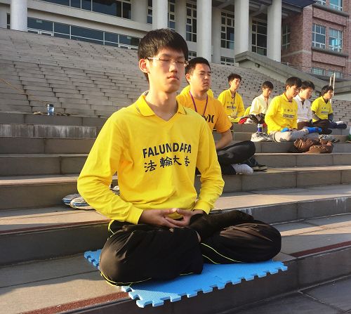 图7. 虎科大研究生陈冠廷(前一)在环球科大校园和青年学子同修一起炼功。
