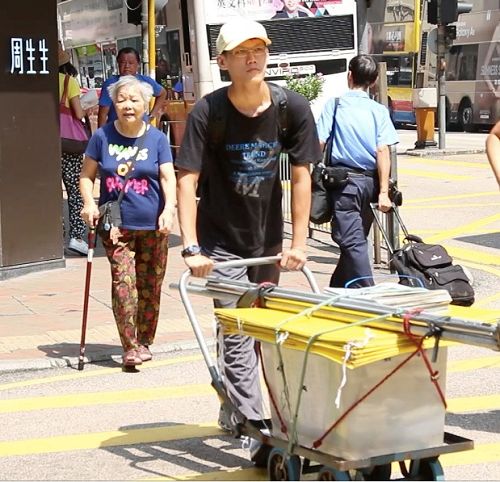 图8. 虎科大研究生陈冠廷(推车者)靠打工收入,积蓄下来的钱做旅费,到香港讲真相,看世人明白真相后的喜悦感到非常欣慰,觉得非常有意义。