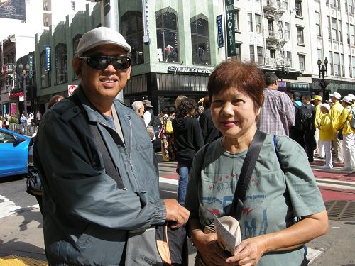 图:马来西亚华人戴先生和太太不停在给法轮功游行队伍拍照。