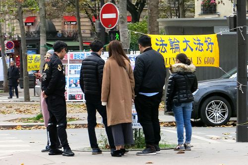 图1-3:来巴黎旅游的中国大陆游客经过世界著名的埃菲尔铁塔附近的法轮功真相点时,许多人驻足阅读真相展板,了解真相。