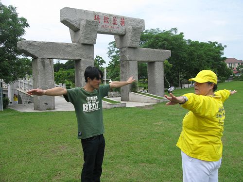 图5:正好经过公园的杨先生看到现场有这么多法轮功学员,很有兴趣的走进了解,经过学员介绍后,他兴起学炼的想法,于是询问起炼功点,并且开始跟学员学炼起来。