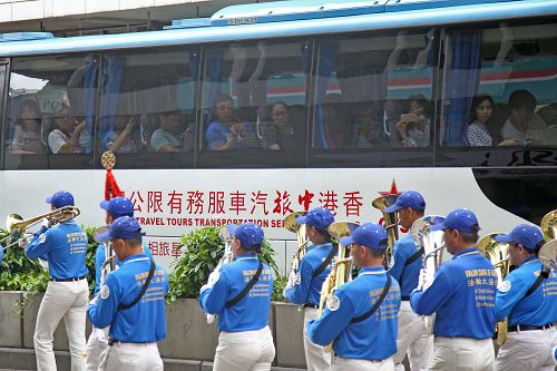 图9:公交车上乘客为法轮功的游行队伍所吸引,举起手机拍照。