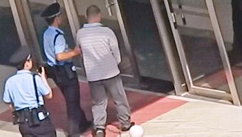 图7:王占青被强制戴手铐、脚镣进入法院