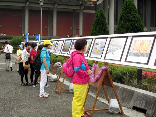 图6-10:法轮功正法之路图片展吸引游客驻足观看。