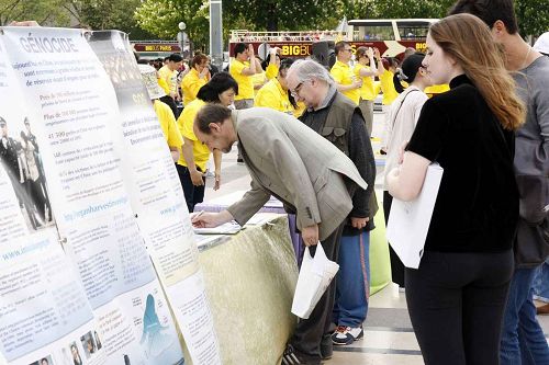 图4:法轮功学员并摆放了真相展板,了解真相后的人们在征签表上签名,支持法轮功学员反迫害,制止迫害。