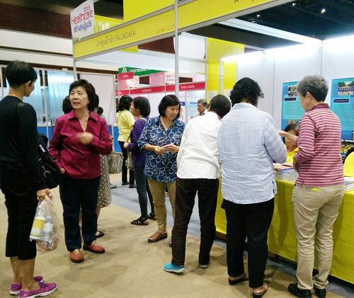图6:二零一六年泰国健康博览会上,人们来法轮功展位了解功法。