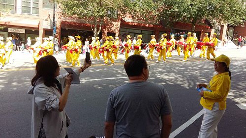 图8:宋女士(左)是从中国大陆来温哥华探亲的游客,她说拍摄法轮功学员的游行队伍,要把美好的画面带回到中国大陆去。