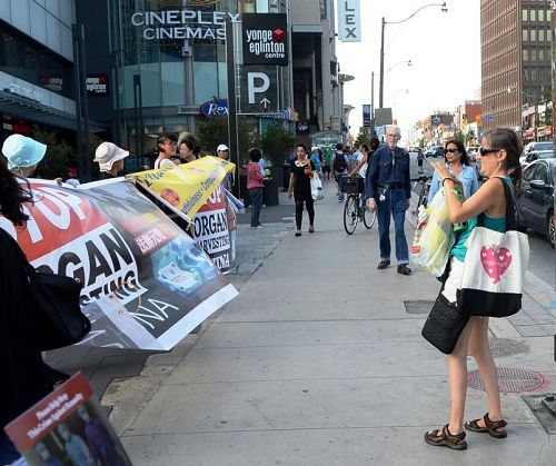 图10:在繁华的Yonge & Eglinton路口,西人女士Lisa路过路口时停下来用手机拍照,表示要放到Facebook上。