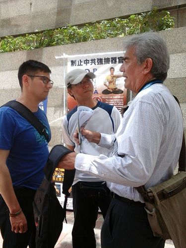 图2:香港法轮功学员在“国际器官移植协会”设置流动真相点,向来往行人讲真相。