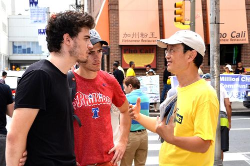 '图12:费城民众向法轮功学员了解真相。'