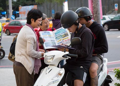 '图2:洵姨(左二)每天到景点发传单、举真相展板,让游客明白“法轮大法好”。'