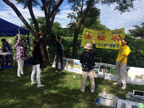 图1-2:在稻泽夏季活动节展位上学炼法轮功的市民们
