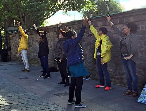 '图4:一位瑞典女士当场学功想亲身感受一下,当学员教完她第三、第四套功法后,满眼的泪水不止,她与学员拥抱连声道谢:“这太美妙了!我一定要学。”'