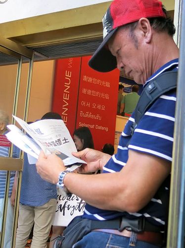 '图2:巴黎拉法耶特商店门前,大陆游客认真阅读《真相报》。'