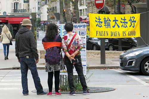 '图3:巴黎埃菲尔铁塔下的退党点上,大陆游客认真观看真相展板。'
