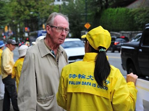 '图4:市民Kennedy先生(左)经过活动地点,仔细聆听现场的法轮功学员讲述真相。'