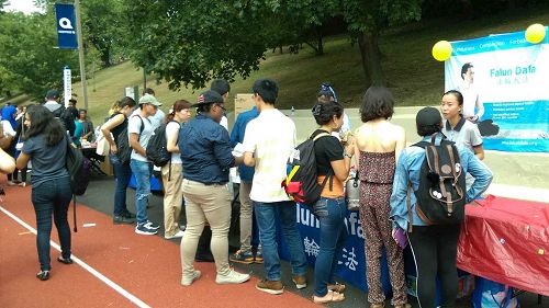 '图1:展位前听学员介绍功法和签名制止中共活摘法轮功学员器官的学生络绎不绝。'