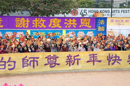 '图:法轮功学员合唱《法轮大法好》后高举福字帖,向市民祝福。'